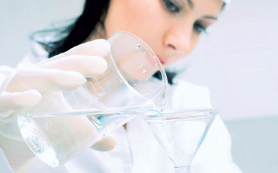 Female scientist filtering water using glass beaker and glass funnel